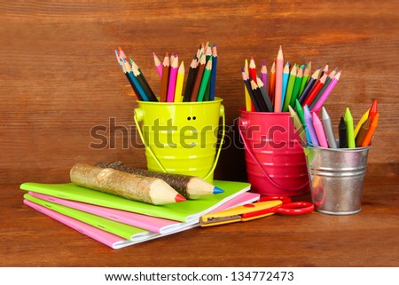 Colorful pencils with school supplies on wooden background