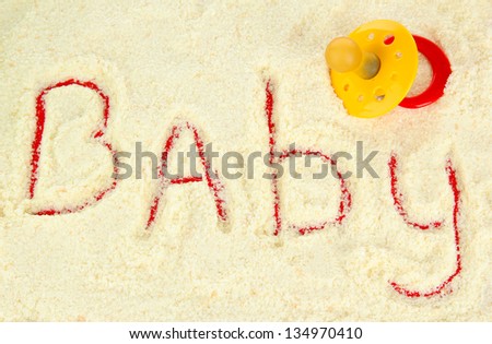 Word baby making with powdered milk on red background