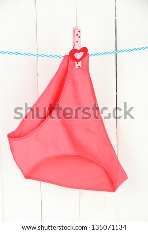 Womans panties hanging on a clothesline, on white wooden background