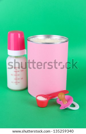 Powdered milk with baby bottle of milk and nipple on green background