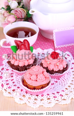 Beautiful strawberry cupcakes and flavored tea on dining table close-up
