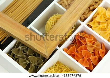 Different types of pasta in white wooden box sections close-up