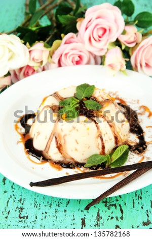 Panna Cotta with chocolate  and caramel sauce and vanilla beans, on color wooden background