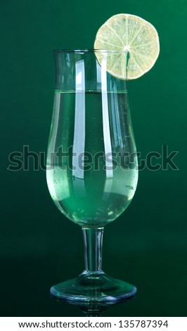 Green cocktail with lime on dark green background