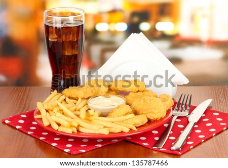 Fried chicken nuggets with french fries,cola and sauce on table in cafe