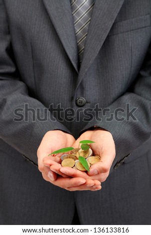 Young businessman with coins and plant isolated on white