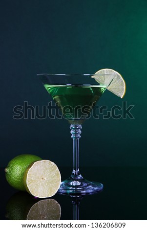 Green cocktail with lime on dark green background