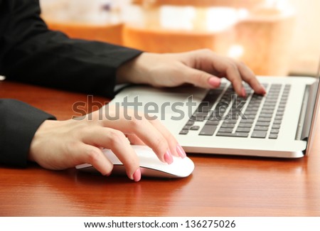 Female hands working on laptop, on bright background
