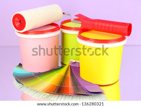 Set for painting: paint pots, paint-roller, palette of colors on lilac background