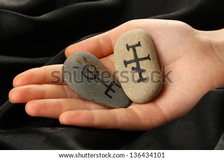 Fortune telling  with symbols on stone in hand on black fabric background
