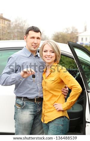 Portrait of happy beautiful couple with car keys, standing near the car
