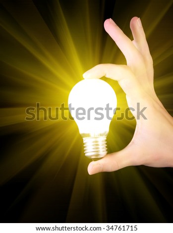 bright yellow incandescent bulb in hand isolated on black background