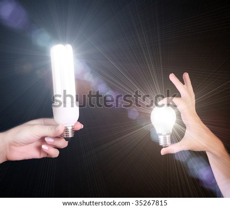 two different light bulbs in hands isolated on black background