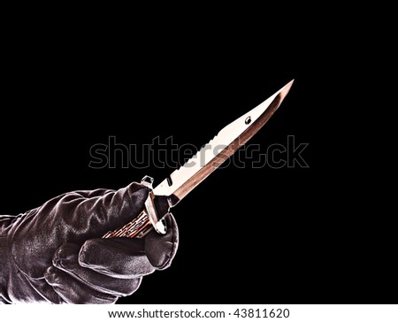 knife in black glove isolated on black