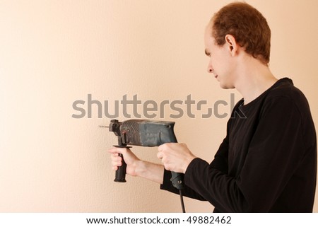 Handsome  young man holding in his hand a big drill working