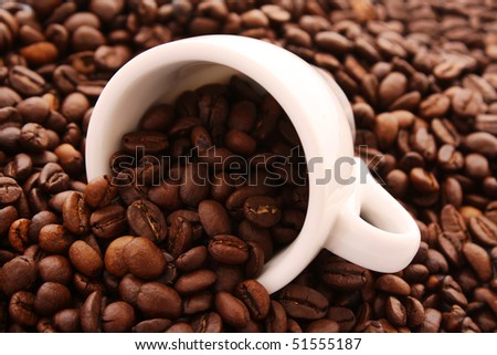 Small white cup of coffee with coffee grain on grain background
