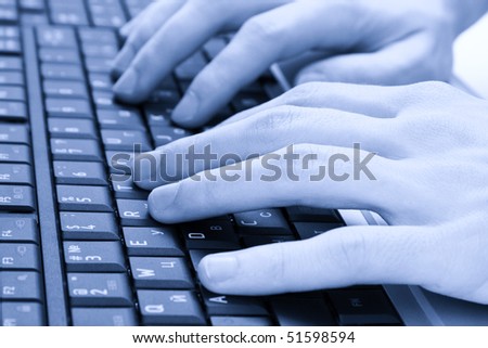 Closeup of male fingers typing a  document on the black laptop. Image in blue tone