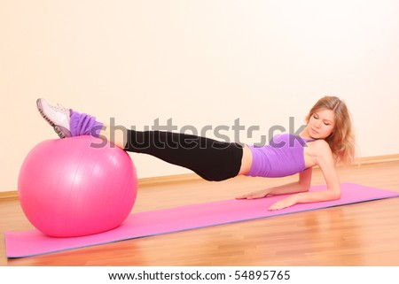 Young beautiful fitness girl with pink ball exercising  in the gym