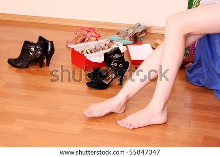 Closeup of a woman leg on floor and many shoes around