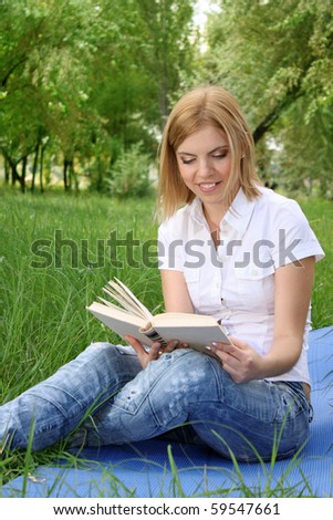 Portrait of young blonde woman reading book in the  park