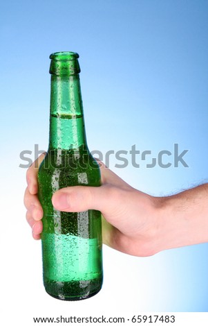 Bottle of beer in hand on blue background