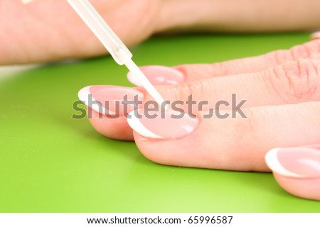 Beautiful woman hands with french manicure on green background