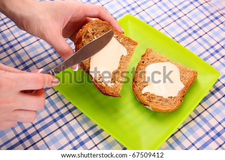 woman hands spread bread with butter on table background