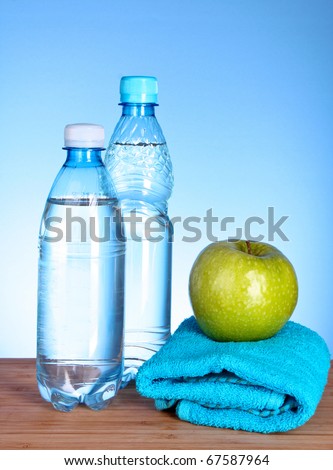 Blue bottle of water, apple and sports towel  on blue background