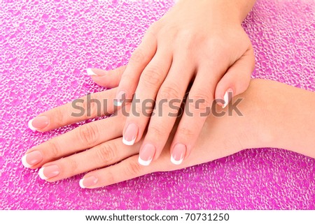 Beautiful woman hands with french manicure on pink background