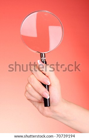 Magnifying glass in woman hand  on red background