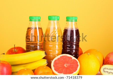 bottles of juice  with ripe fruits on yellow background