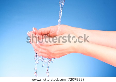 Human hands with water splashing on them with blue background