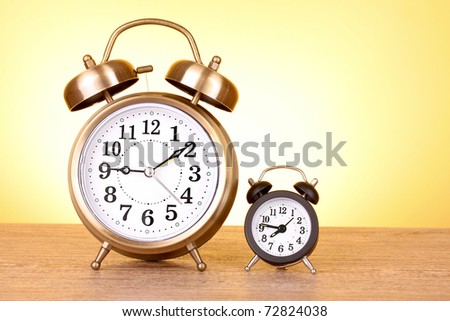 Two clocks with different time on yellow background