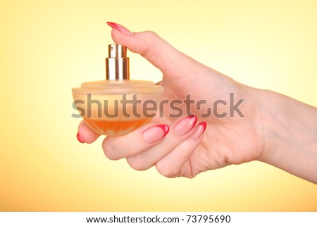 bottle of perfume in the hand  on yellow background