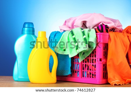 Bright clothes in a laundry basket on blue background