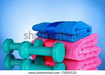 sports towel and dumbbells on blue background