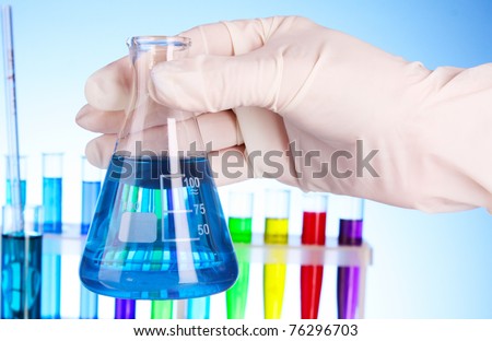 Conical flask with blue liquid on blue background with test-tubes