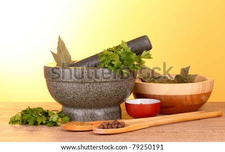 Mortar and pestle, bowls, parsley and pepper on yellow background