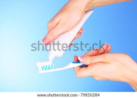 Tooth-paste and brush in the  hand on blue background