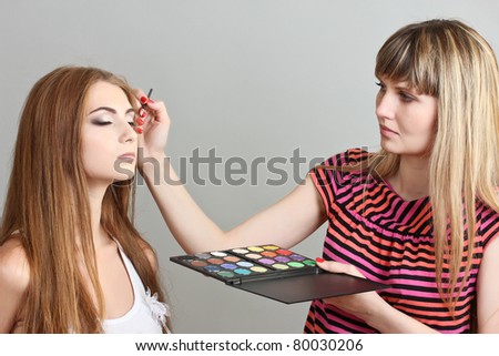 Make-up artist applying eye shadows on beautiful model