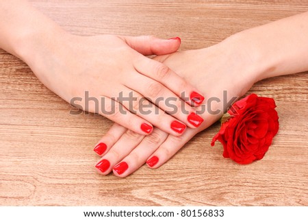 beautiful woman\'s hands and rose on wooden background
