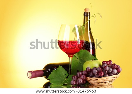 Red wine and fruits on yellow background