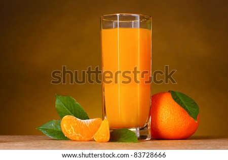 Glass of healthy fresh juice of mandarins on brown background