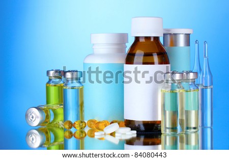 Medical bottles, ampoules and pills on blue background