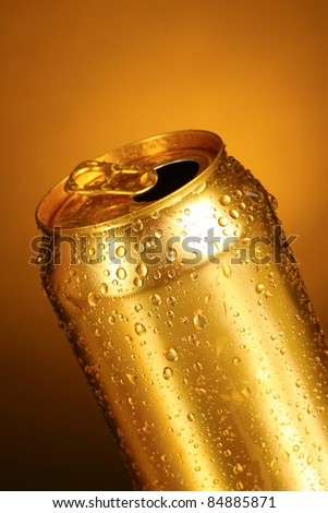 gold tin can on a yellow background. Focus on nearest water drops