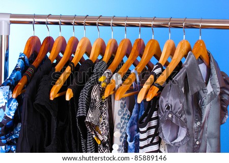 different clothes on wooden hangers on blue background