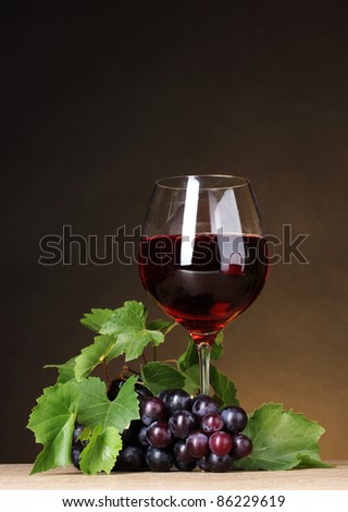 Glass of wine and grapes on yellow background
