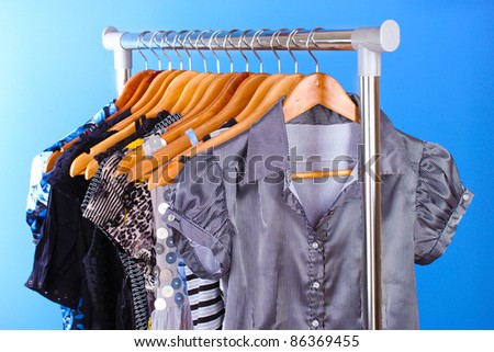 different clothes on wooden hangers on blue background