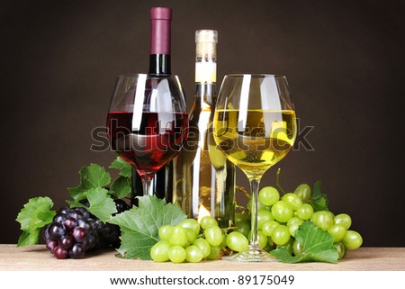 Glasses of wine, bottles and grapes on yellow background