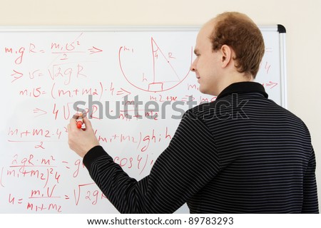 man writing math formulas on a white-board